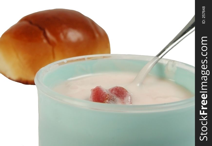 Breakfast set containing a strawberry yogurt cup and a croissant.The focus is on the cup,the croissant is blurred.