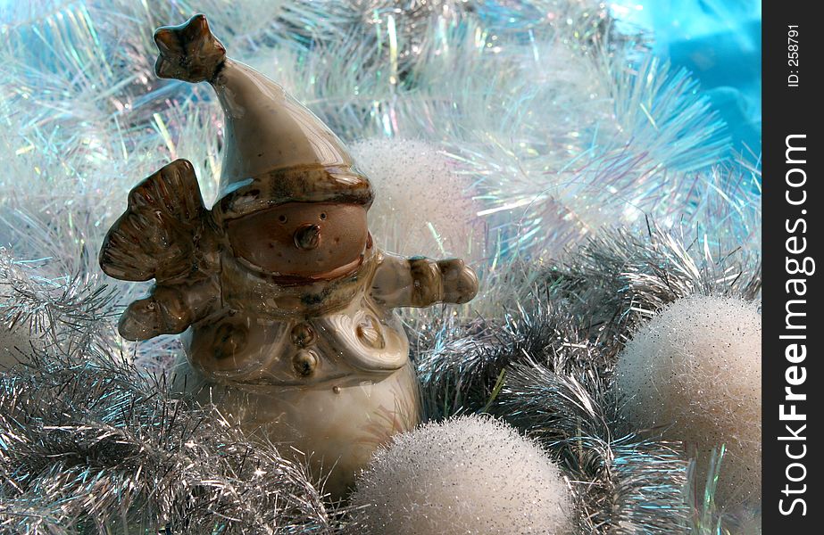 Ceramic snowman nestling in silver tinsel with white snowballs. Ceramic snowman nestling in silver tinsel with white snowballs