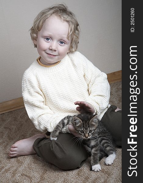 Little smiling blond adorable boy and kitten playing at home. Little smiling blond adorable boy and kitten playing at home