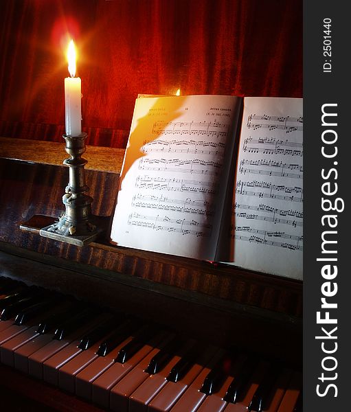 Retro still life with sheet music and piano at candle light