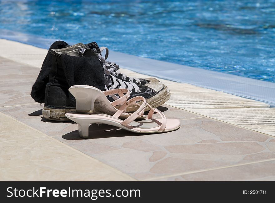 Two pairs of old shoes on edge of a pool. Two pairs of old shoes on edge of a pool