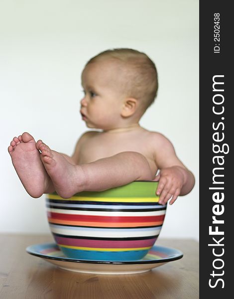 Image of an adorable baby sitting in a colorful, over-sized teacup. Image of an adorable baby sitting in a colorful, over-sized teacup