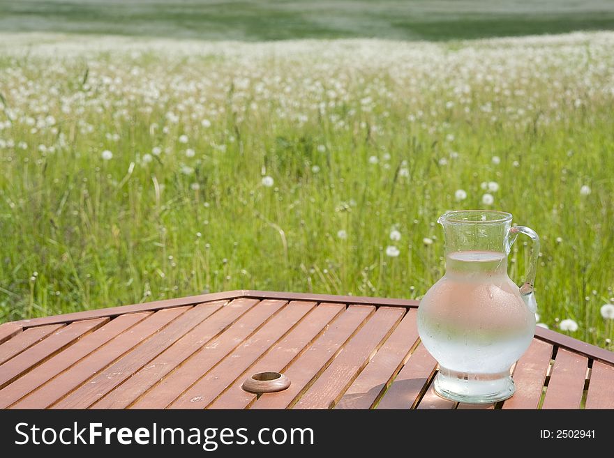 Jug wit cold water on table in the grassland