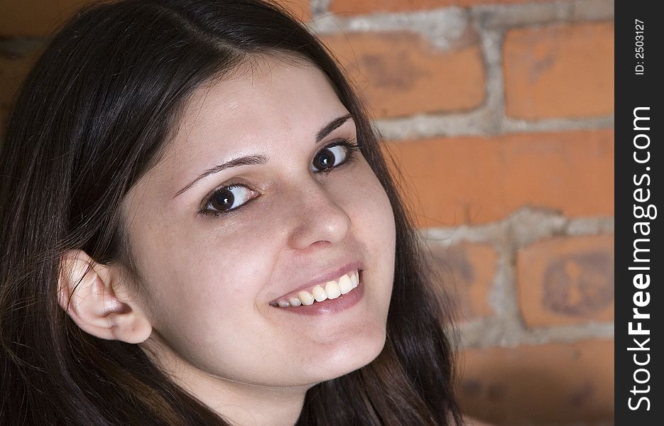 Headshot of a beautiful young brunette woman in front of a grungy brick background. Headshot of a beautiful young brunette woman in front of a grungy brick background.