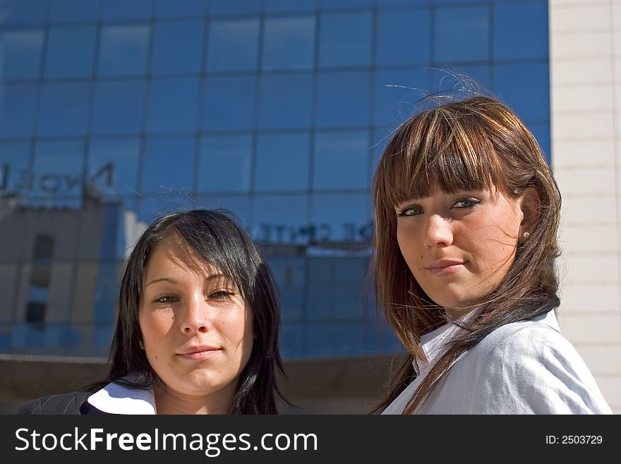 Portrait of two young women with building behind