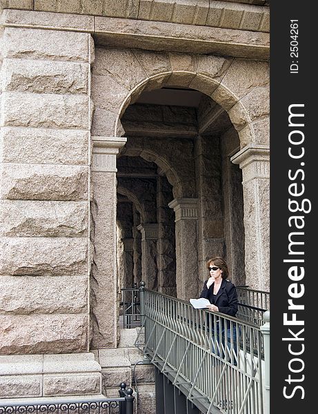 The arched entry of a large public building with a woman lawyer standing on a ramp leading up to it. The arched entry of a large public building with a woman lawyer standing on a ramp leading up to it.