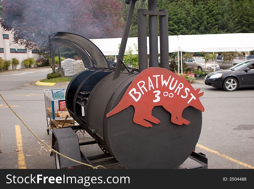 Barbecue barrel cooking bratwurst for sale. This is a street vendor setup. Barbecue barrel cooking bratwurst for sale. This is a street vendor setup.