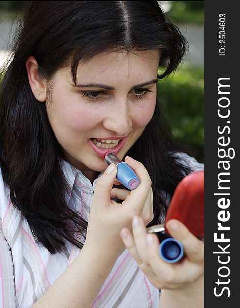 Woman doing evening make-up for lips and holding a mirror