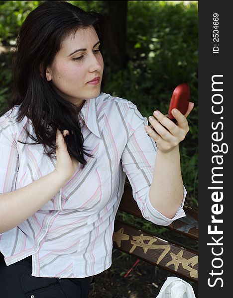 Woman doing evening make-up for lips and holding a mirror