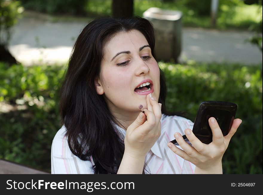 Woman doing evening make-up for lips and holding a mirror