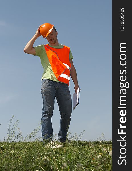 Man in clothes of the builder on a grass on a background of the dark blue sky. Man in clothes of the builder on a grass on a background of the dark blue sky