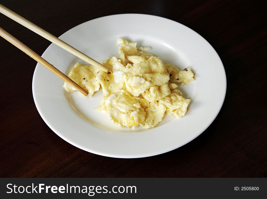 Scrambled Egg And Chopsticks On A White Plate On A Dark Wooden Table