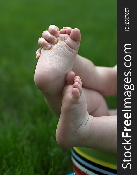 Image of a baby's feet peeking out over the side of a colorful cup. Image of a baby's feet peeking out over the side of a colorful cup