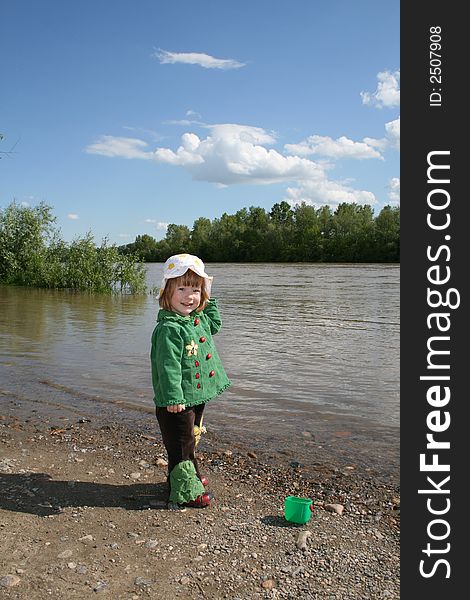 Small girl in green plays ashore rivers. Small girl in green plays ashore rivers