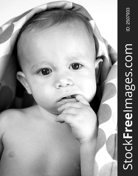 Black and white image of a cute toddler peeking out from under a blanket. Black and white image of a cute toddler peeking out from under a blanket