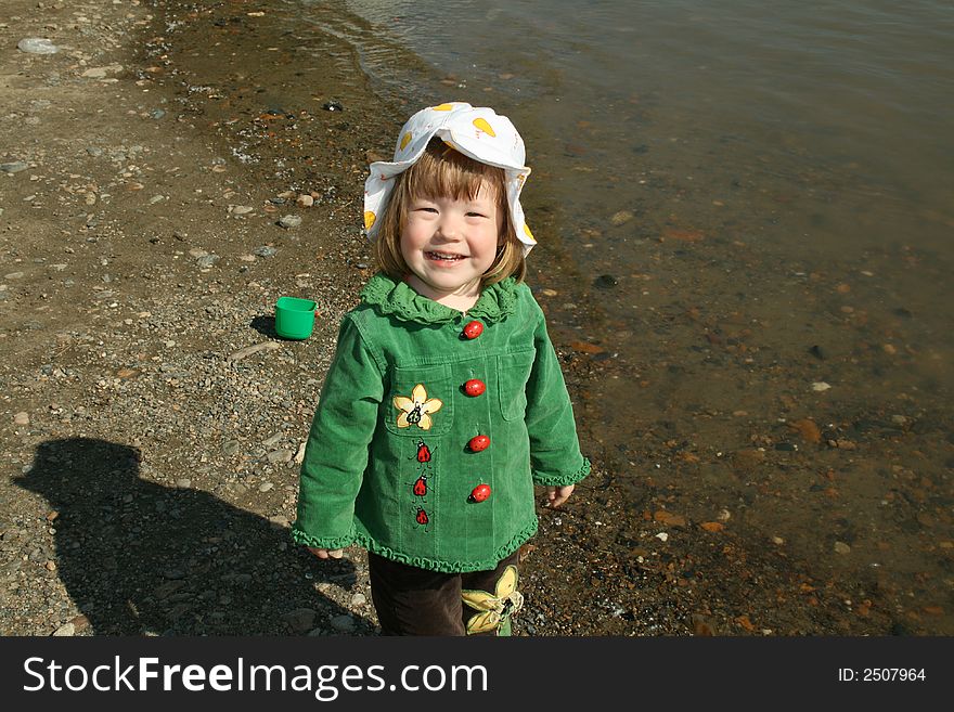 Small girl in green plays ashore rivers. Small girl in green plays ashore rivers