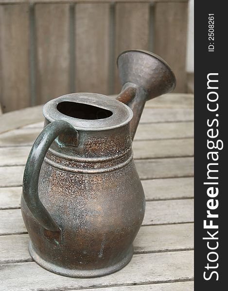 Isolated garden watering jug on wood table