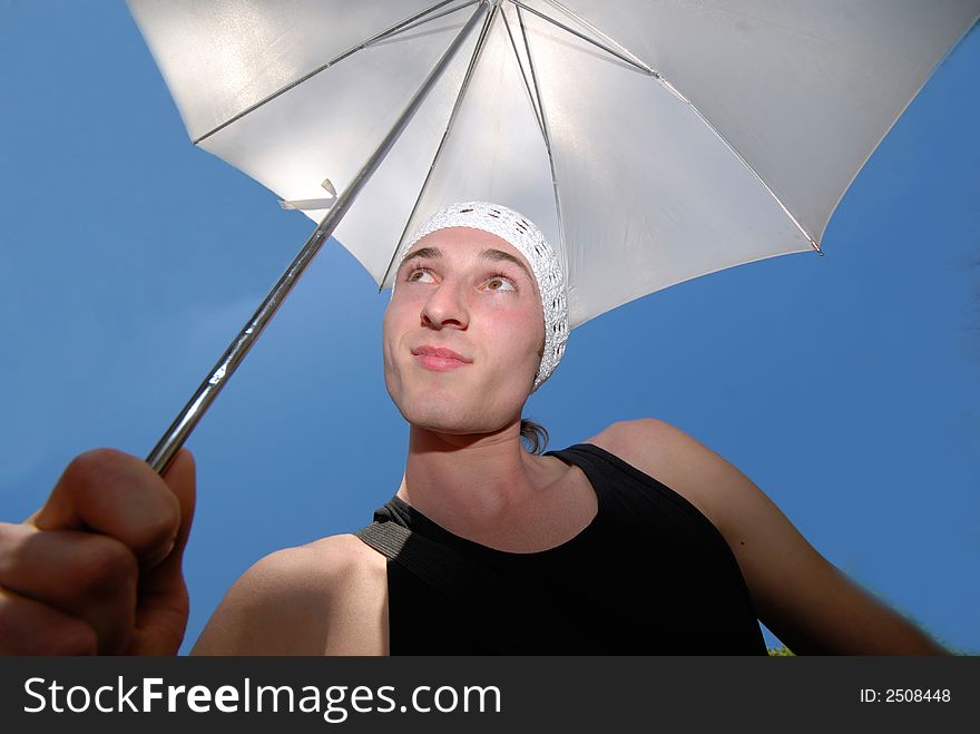 Guy with  white umbrella in  white cap on  head on  background of  dark blue sky. Guy with  white umbrella in  white cap on  head on  background of  dark blue sky