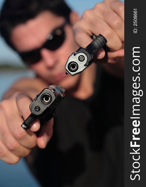 A man holding a pistol and pointing it at the camera. (This image is part of a series). A man holding a pistol and pointing it at the camera. (This image is part of a series).