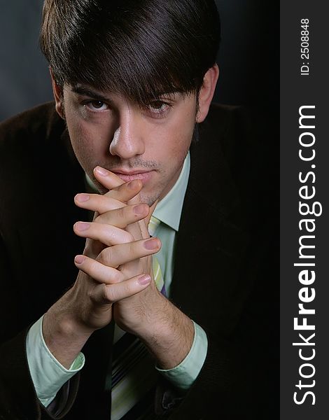 Young business man sitting with folded hands