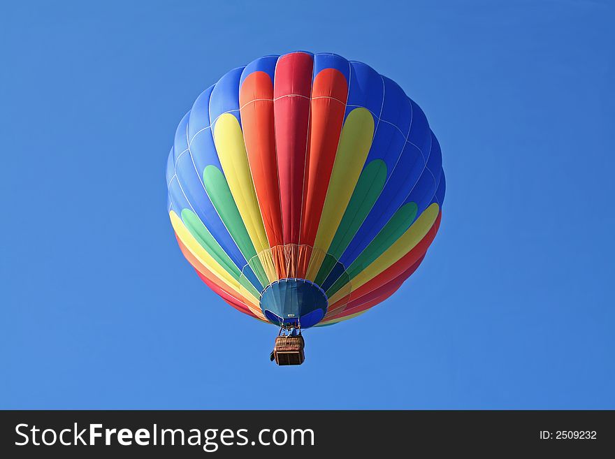 Single colorful hot air balloon ascending into bright blue sky. Single colorful hot air balloon ascending into bright blue sky