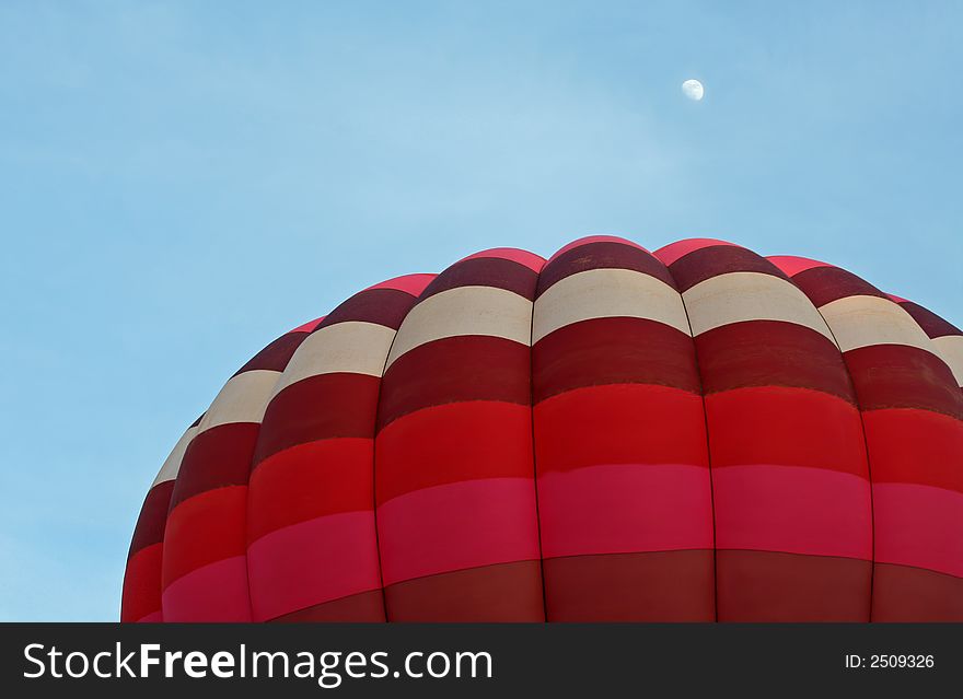 Hot air balloon ascending during evening with moon shining above. Hot air balloon ascending during evening with moon shining above