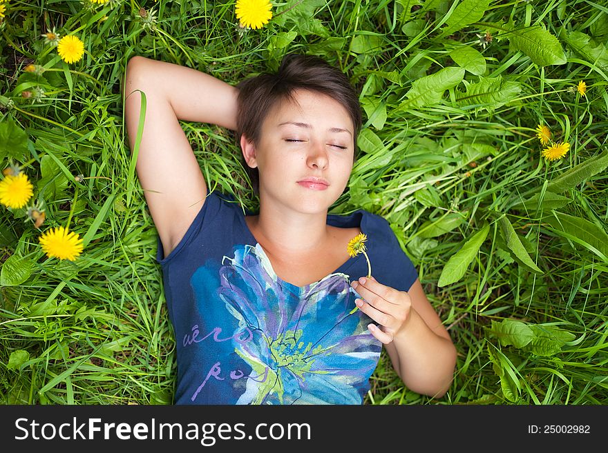 Girl on dandelion on green spring field