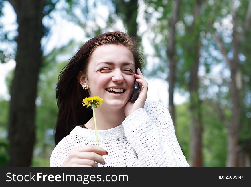 Smiling beauty teenage girl with dandelion talking on mobile phone. Smiling beauty teenage girl with dandelion talking on mobile phone