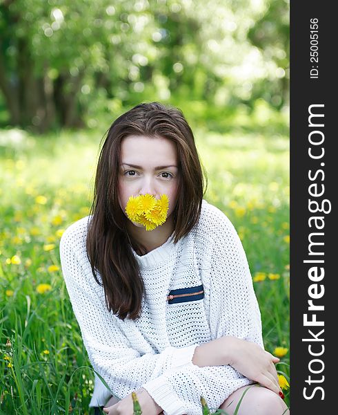 Beauty teenage girl with yellow dandelions in her mouth on green summer background. Beauty teenage girl with yellow dandelions in her mouth on green summer background