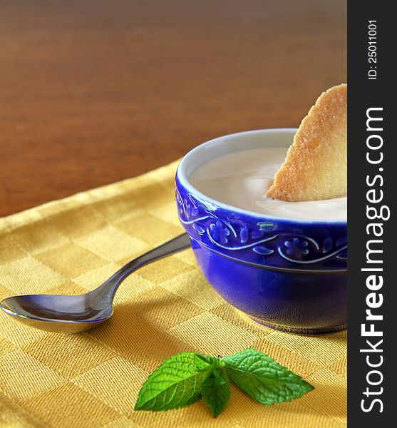 White yogurt in a blue bowl with simple biscuit
