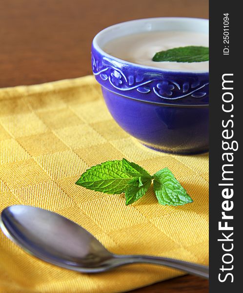 White yogurt in a blue bowl with green mint leaf. White yogurt in a blue bowl with green mint leaf