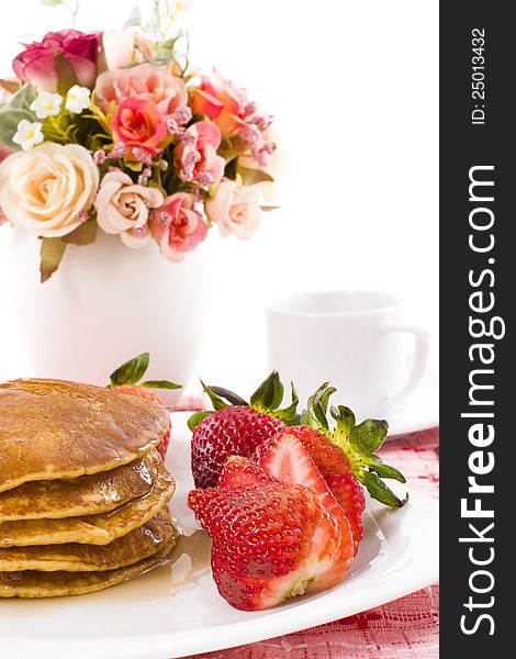 Pancake and strawberry have maple syrup on top with coffee. Pancake and strawberry have maple syrup on top with coffee