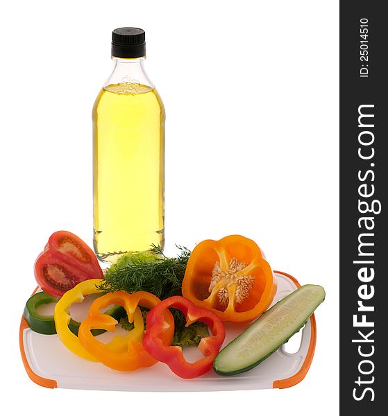 Sliced vegetables at plastic cutting board and a bottle of oil isolated on white. Sliced vegetables at plastic cutting board and a bottle of oil isolated on white