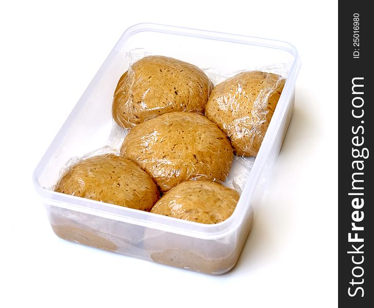 Five circle shaped dough pieces wrapped in nylon within a plastic container