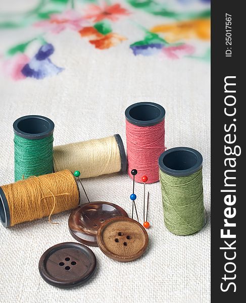 Many bobbin of thread with needle and button on table