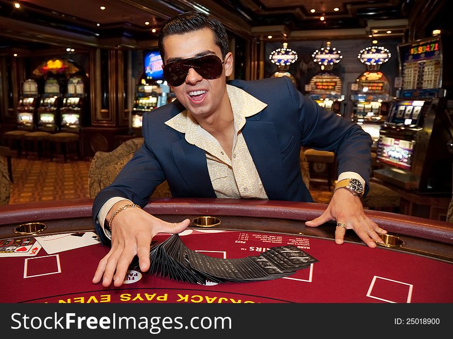 Young man in trendy clothes playing cards in casino. Young man in trendy clothes playing cards in casino