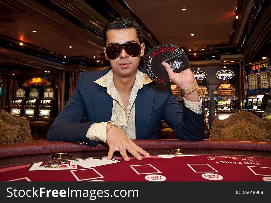 Young man in trendy clothes playing cards in casino. Young man in trendy clothes playing cards in casino