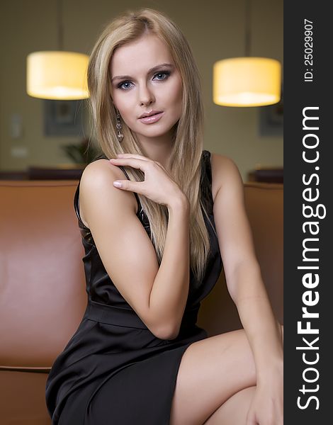 Attractive blond woman in black dress sitting on the couch