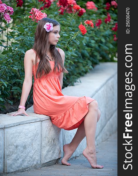 Photo of beautiful fresh teenager girl with expressive look posing on a background of flowerbeds. Photo of beautiful fresh teenager girl with expressive look posing on a background of flowerbeds