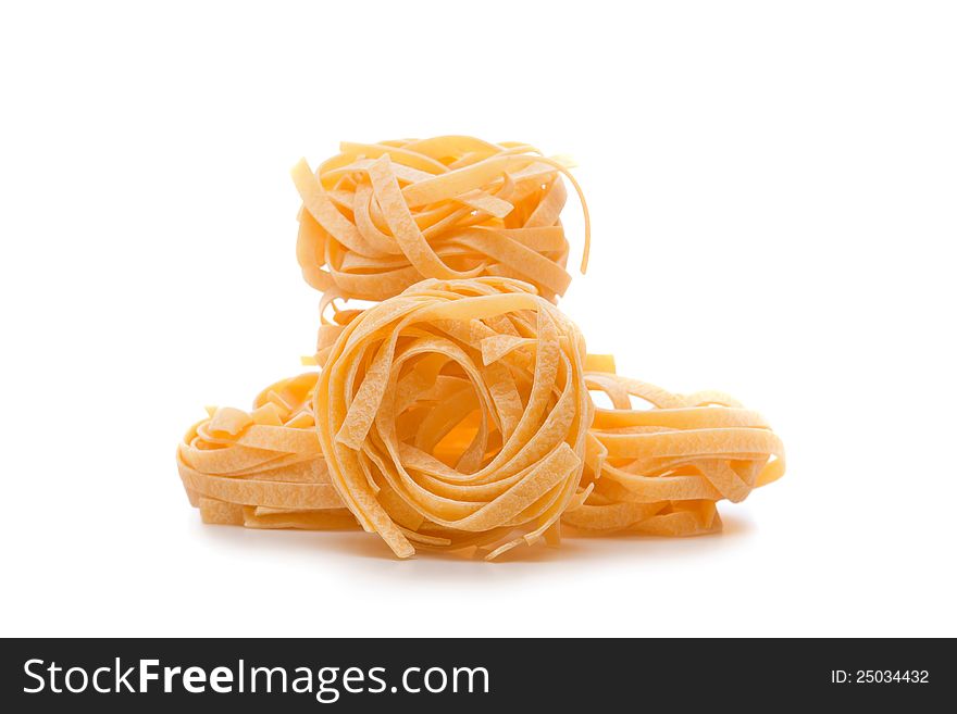 Three uncooked pasta nests with soft shadow on white background