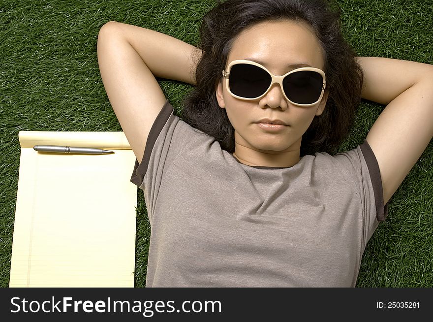 Woman laying on the green grass on the summer. You can put your message on the paper. Woman laying on the green grass on the summer. You can put your message on the paper