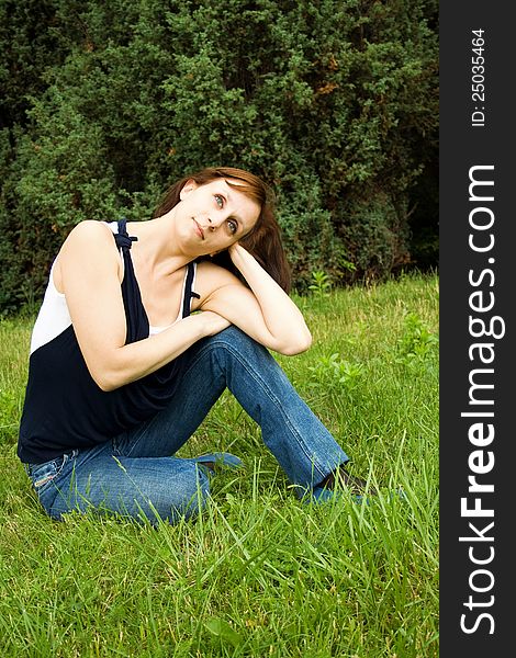 Young happy woman sitting on the green grass