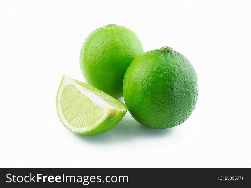 Two green limes and slice on white background