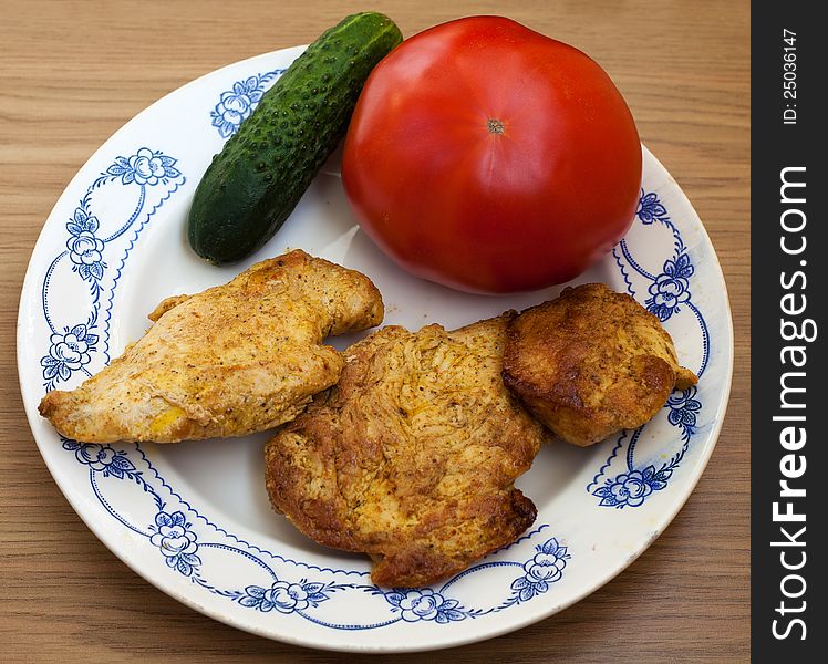 Three pieces of roasted meat with tomato and cucumber on the plate