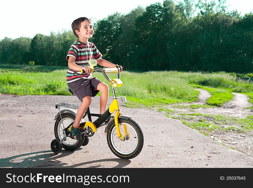 Little boy riding bike on country road outdoors in sunny day