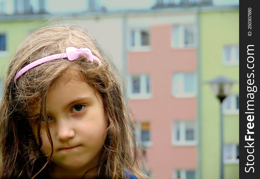 offended little Polish girl with an armband in her hair against the background of apartment blocks. offended little Polish girl with an armband in her hair against the background of apartment blocks