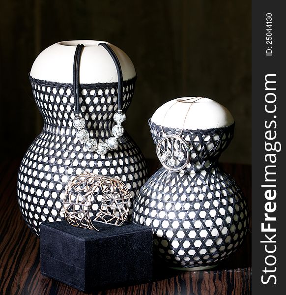 Set of silver necklaces and bracelet shown on ceramic vases