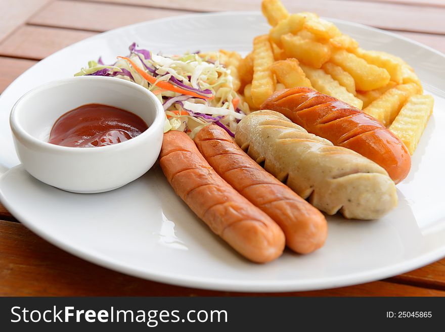 Mixed sausage served with french fried in the white dish put on the wood table