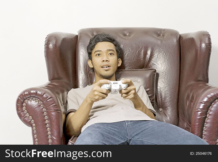 Young male playing video game on the couch on living room