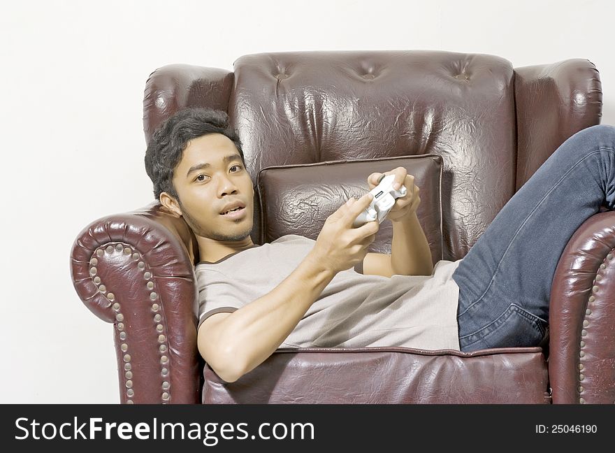 Young male playing video game on the couch on living room